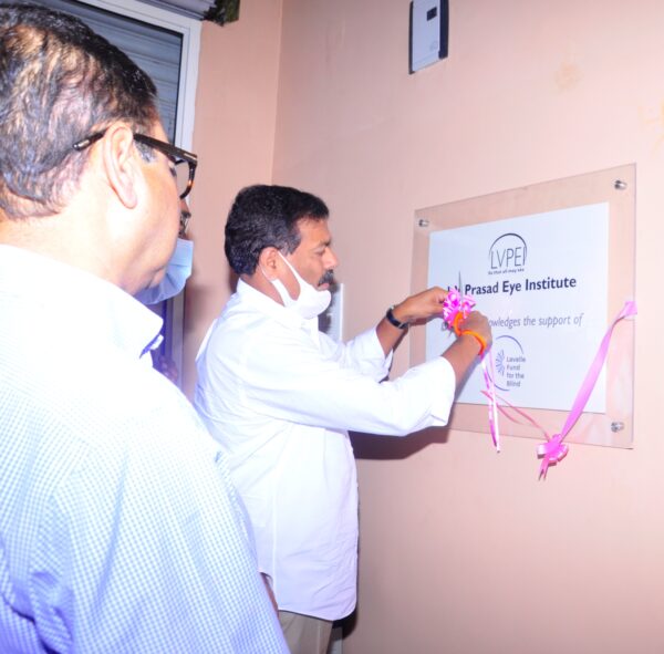 Man putting ribbon around wall plaque acknowledging Lavelle Fund's support of LVPEI.