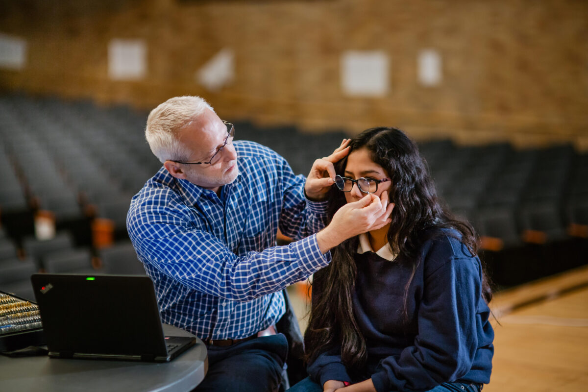 An optometrist tests a female student for eyeglass prescriptions.