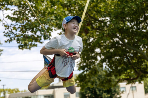 Harnessed in and mid-air, a camper bursts into laughter on the Air Jumper. This unforgettable moment reflects how camp empowers children with vision loss to soar—literally and figuratively.