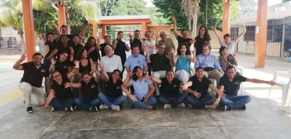 Staff members from the FUNDAL School in Guatemala and select Board members and staff from the Lavelle Fund in a group shot outdoors with hands raised and lots of smiles.