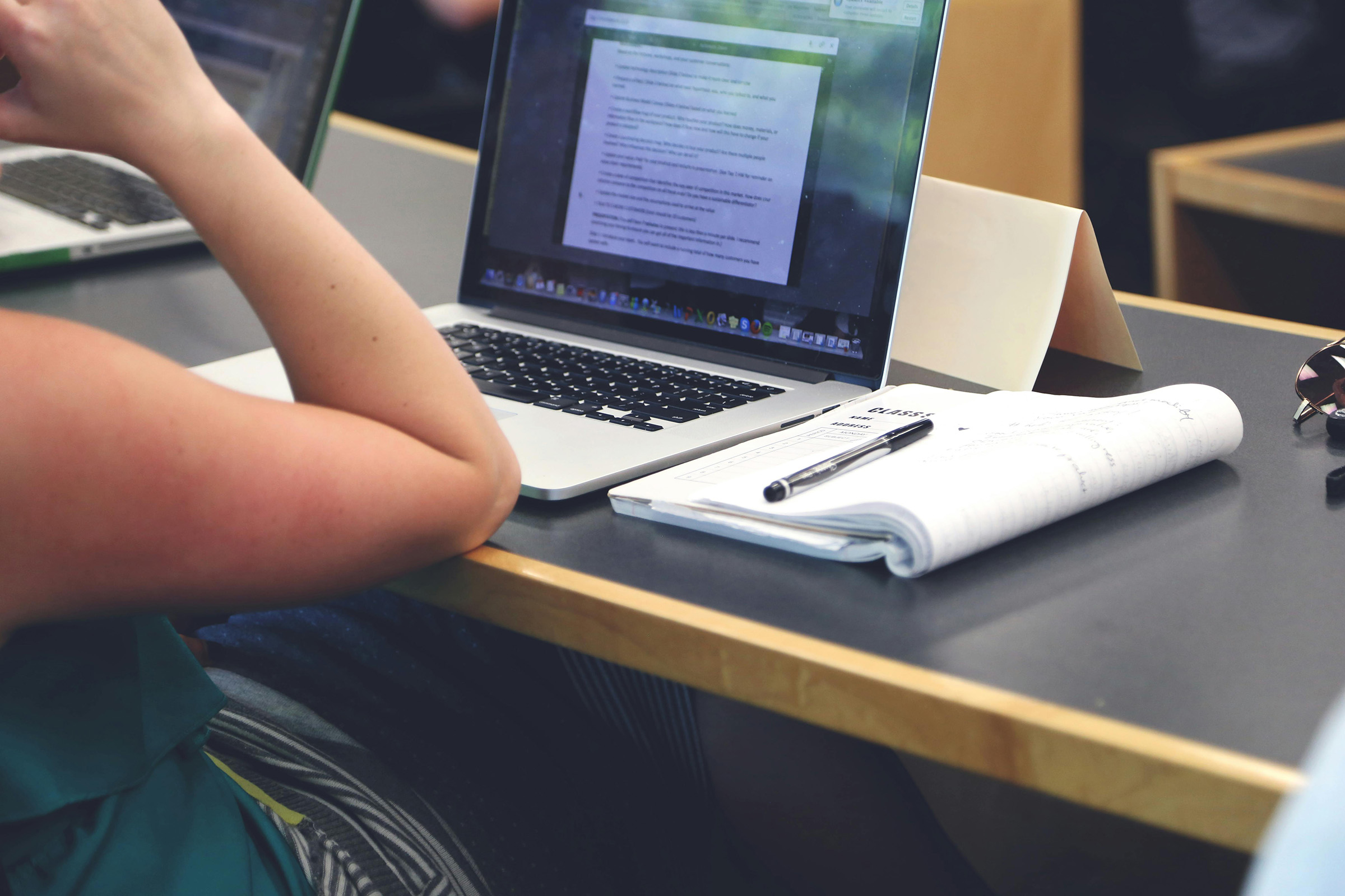 Student at their desk with an open laptop and notebook.
